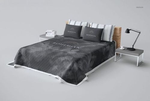 Top view of a plain and quilted bed coverlet mockup in dark tones, draped over a wooden bed with striped pillows.