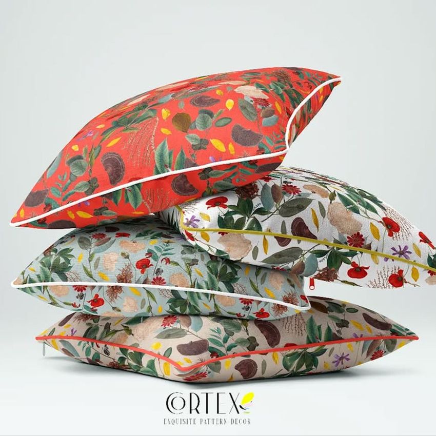 Reversible piped cushions mockup showing four stacked pillows with colorful botanical patterns on a plain light background.