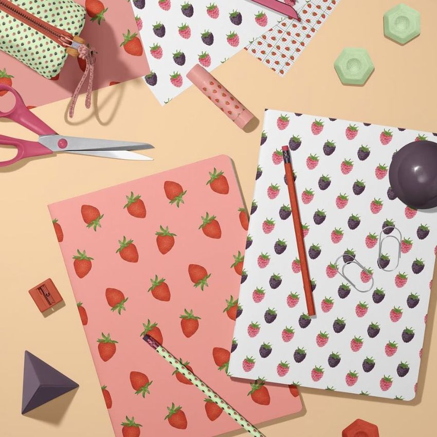 Stationery mockup featuring two classic A4 notebooks with strawberry patterns, surrounded by pencils, scissors, and geometric props on a pastel surface.