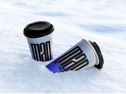 Winter-themed PSD mockup with two drinkware paper cups, black lids, and large text design resting in snowy surroundings.