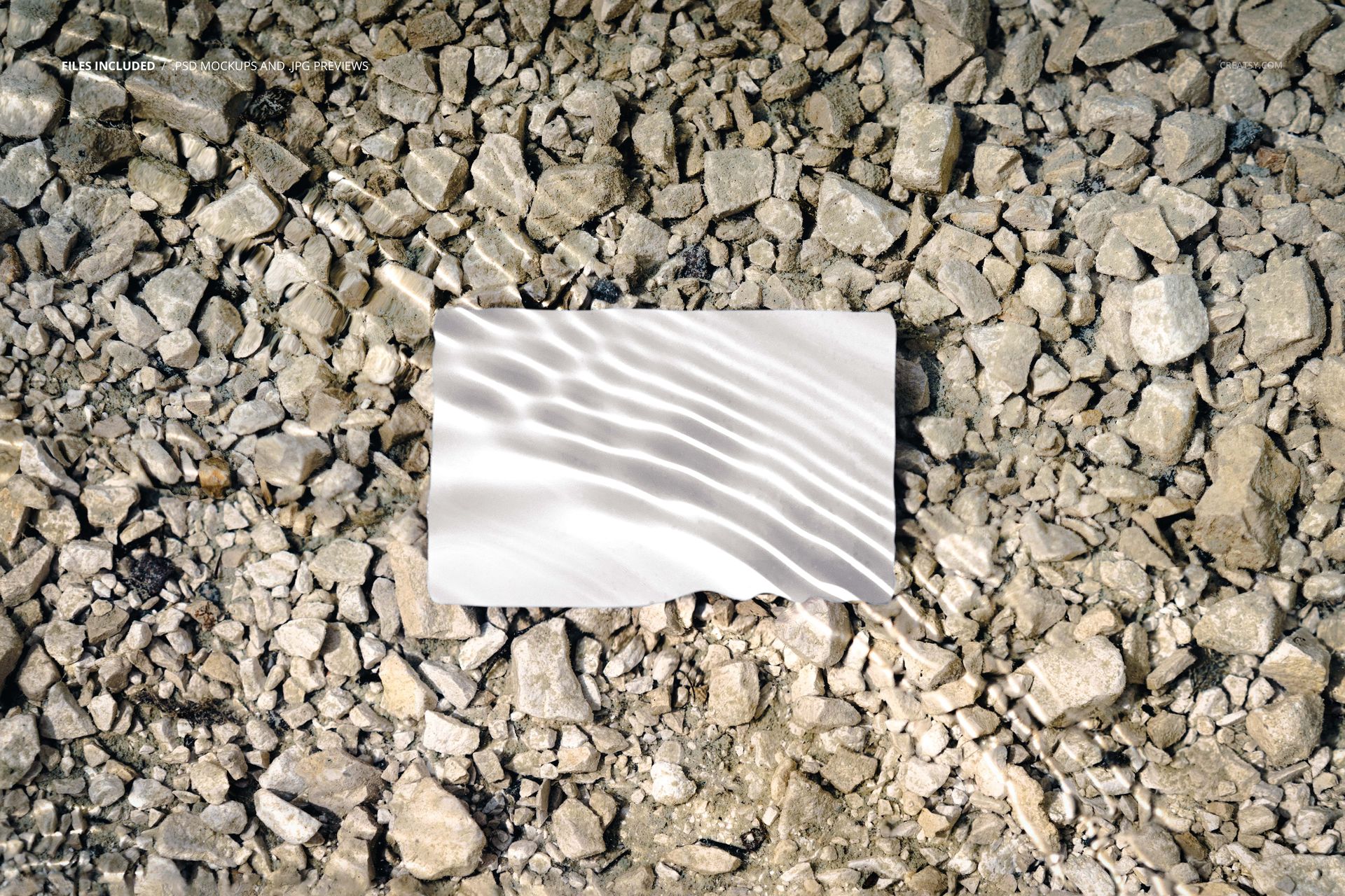 Rectangular business card mockup with blank white surface placed on rocky ground under clear water, top view.