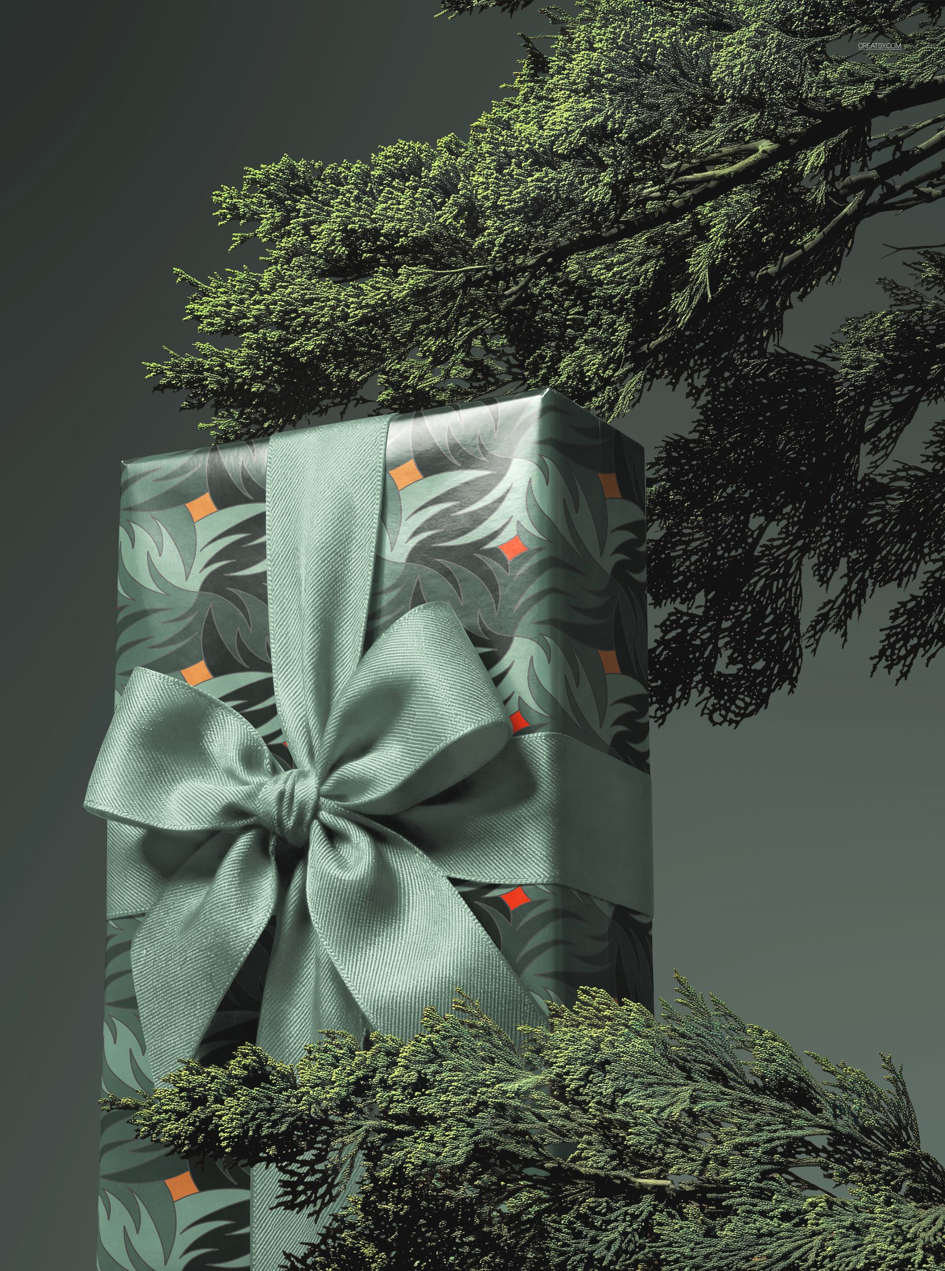 Tall rectangular gift box mockup with green foliage wrapping paper and a matching satin ribbon, set among pine branches.