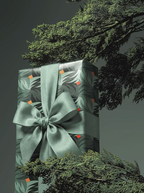Tall rectangular gift box mockup with green foliage wrapping paper and a matching satin ribbon, set among pine branches.