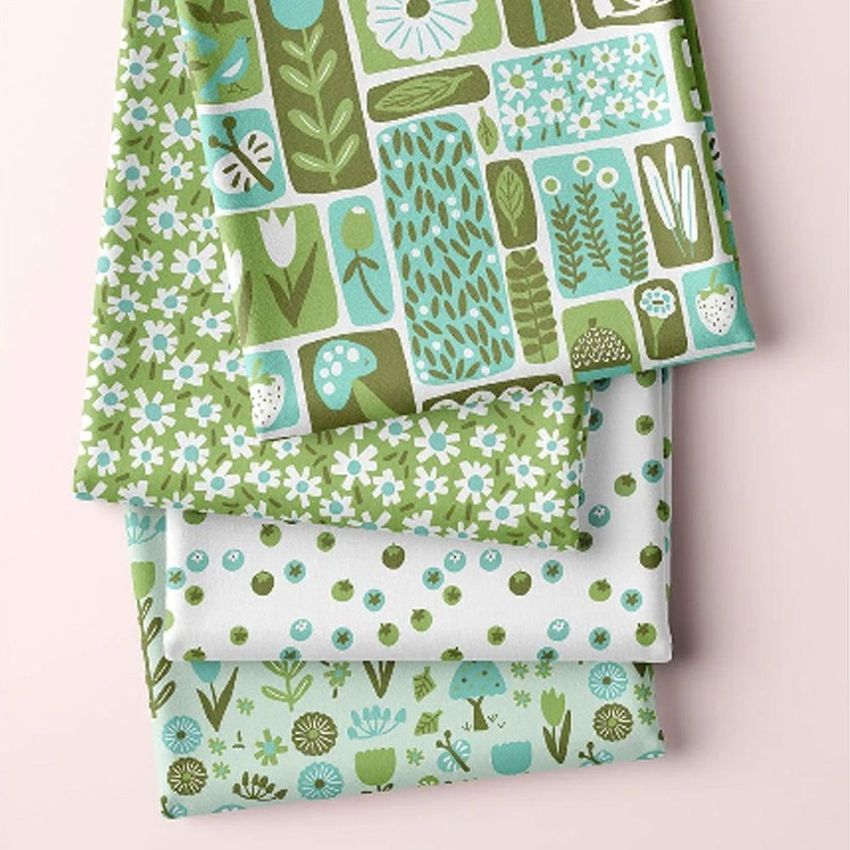 Folded fabrics mockup featuring three layers with spring-themed patterns in green, blue, and white on a pale background.