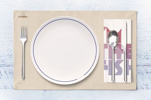 Seafood restaurant mockup featuring a round white plate, silverware, and folded napkin on a neutral placemat.