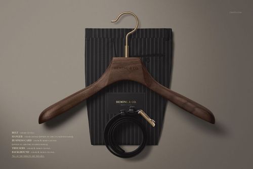 Top view of a men's fashion mockup set featuring a dark wood hanger, pinstriped pouch, coiled black belt, and card.
