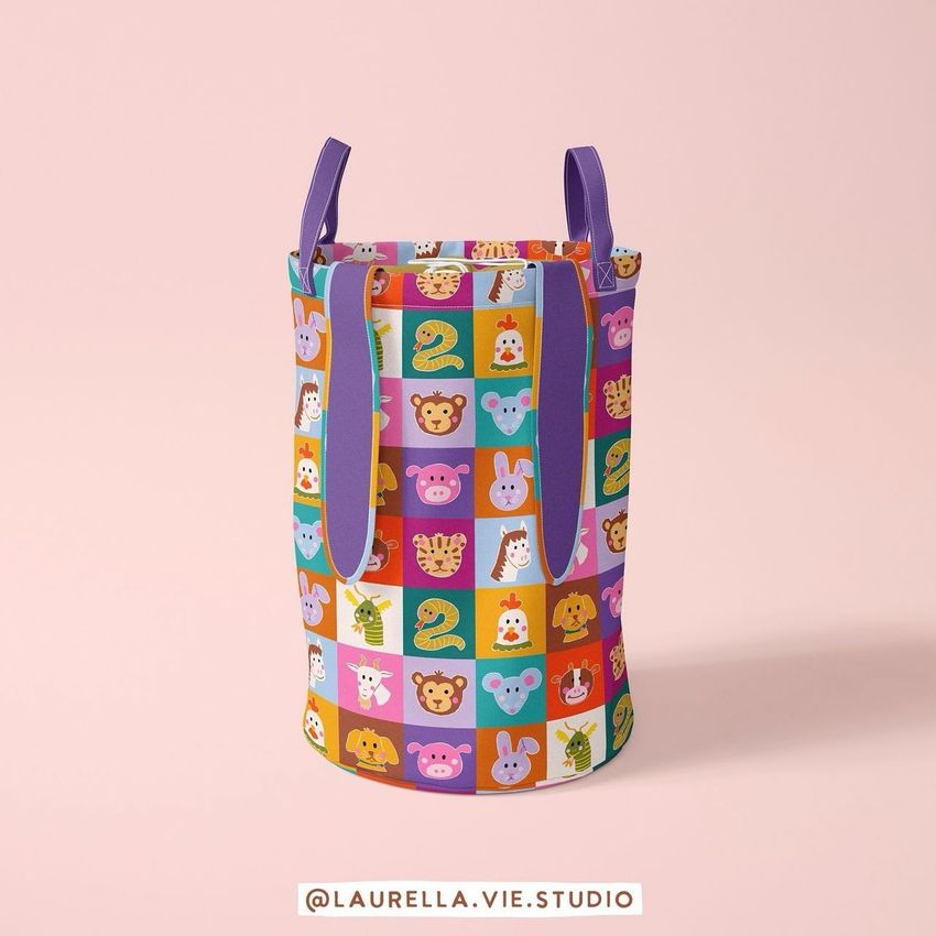 Kids storage basket mockup with colorful animal and number pattern on a pink background, shown from a front angle with purple handles.