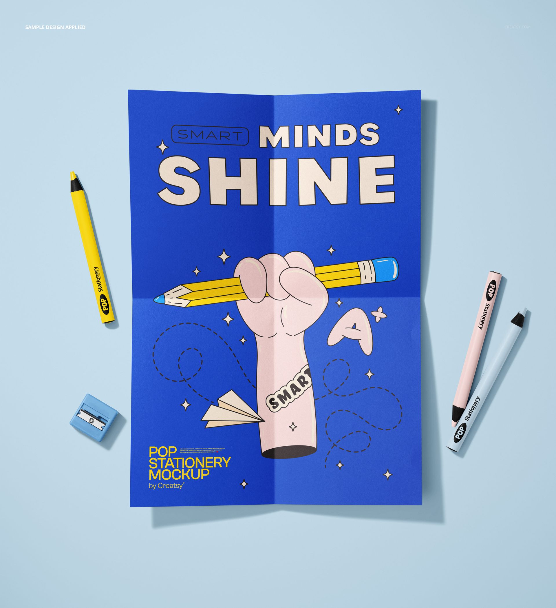Folded poster mockup shown from a top view on a light blue surface, surrounded by crayons and a pencil sharpener.