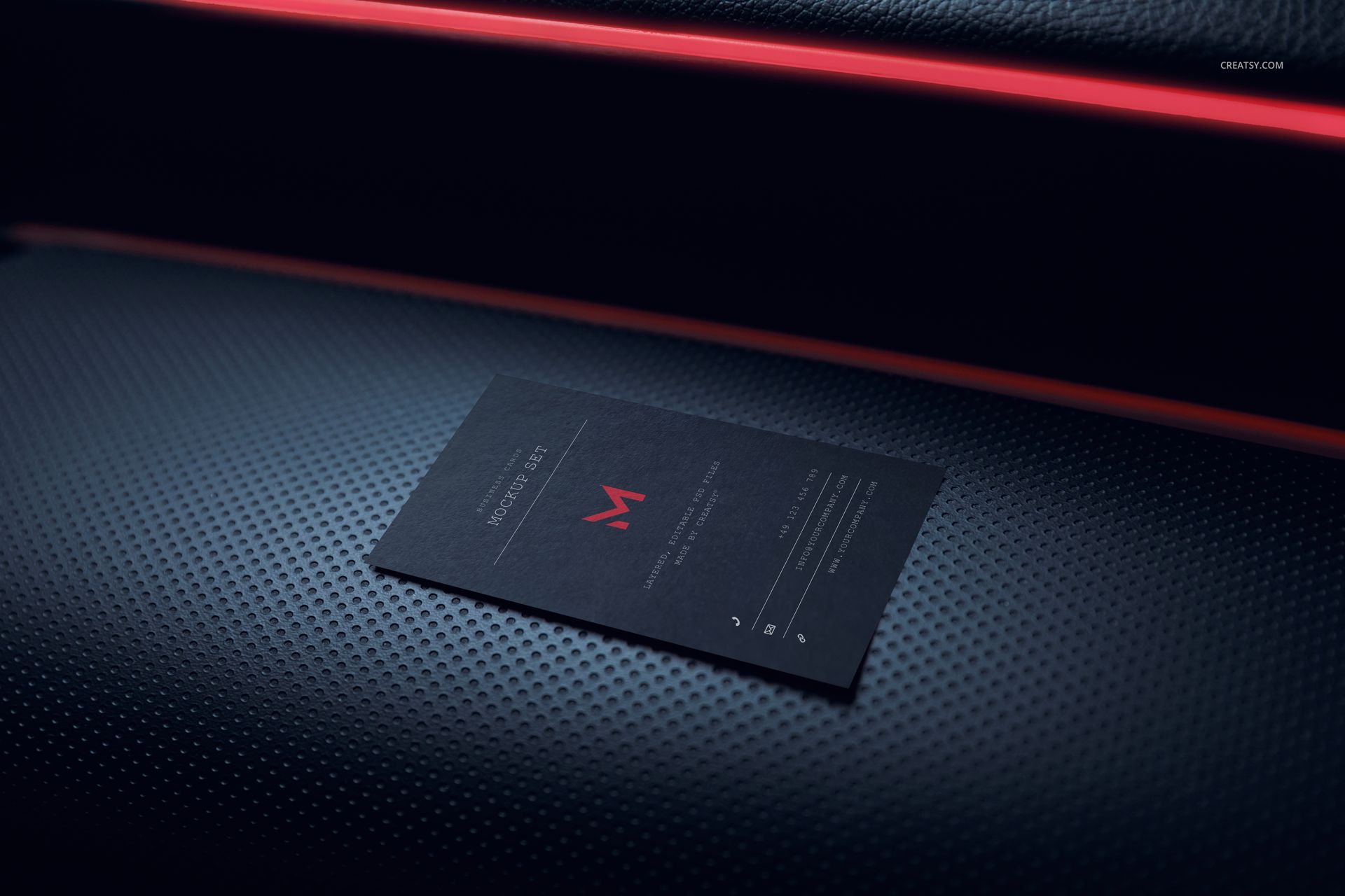 Single black business card mockup placed on a perforated car interior panel with red trim, close-up perspective.