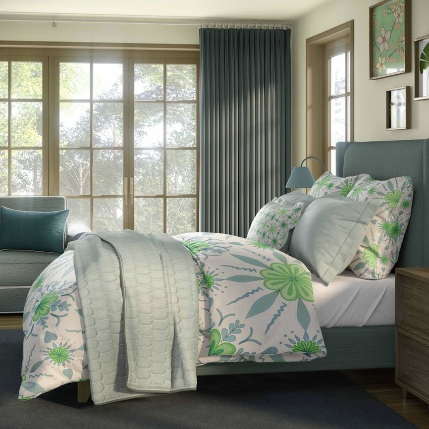 Bedroom bedding set mockup featuring a bed with floral-patterned duvet and pillows in green and blue tones, set against large windows.