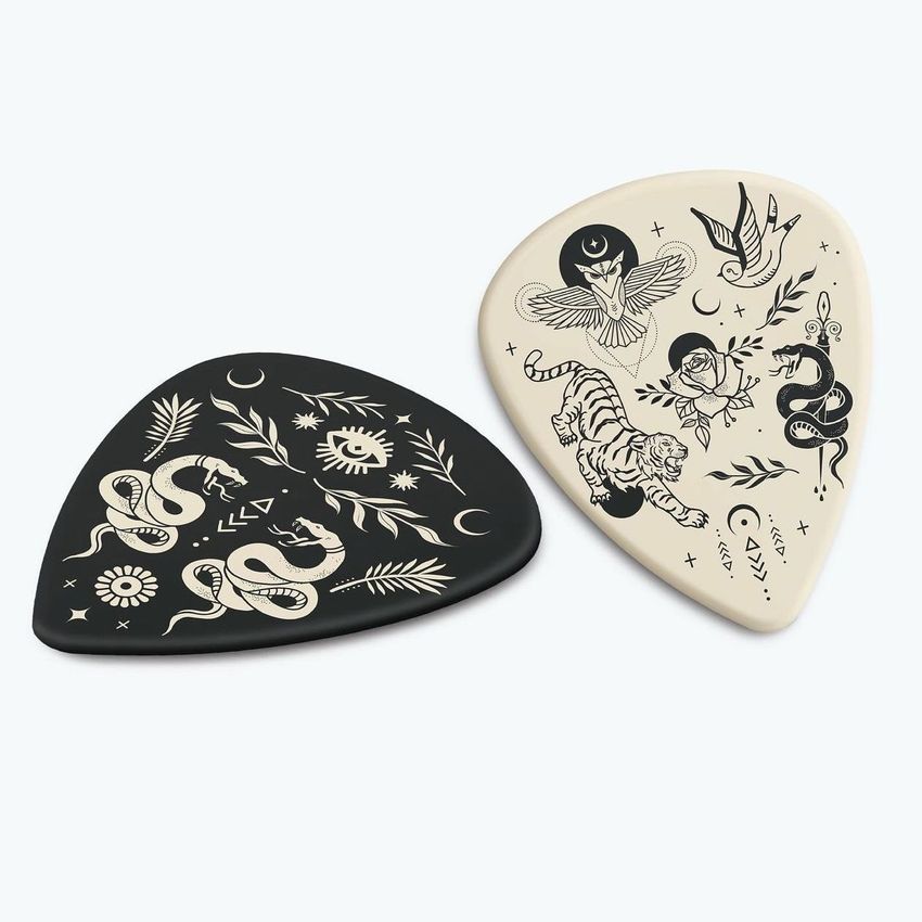 Guitar pick mockup featuring two picks with tattoo-style illustrations, one black and one cream, on a light background.
