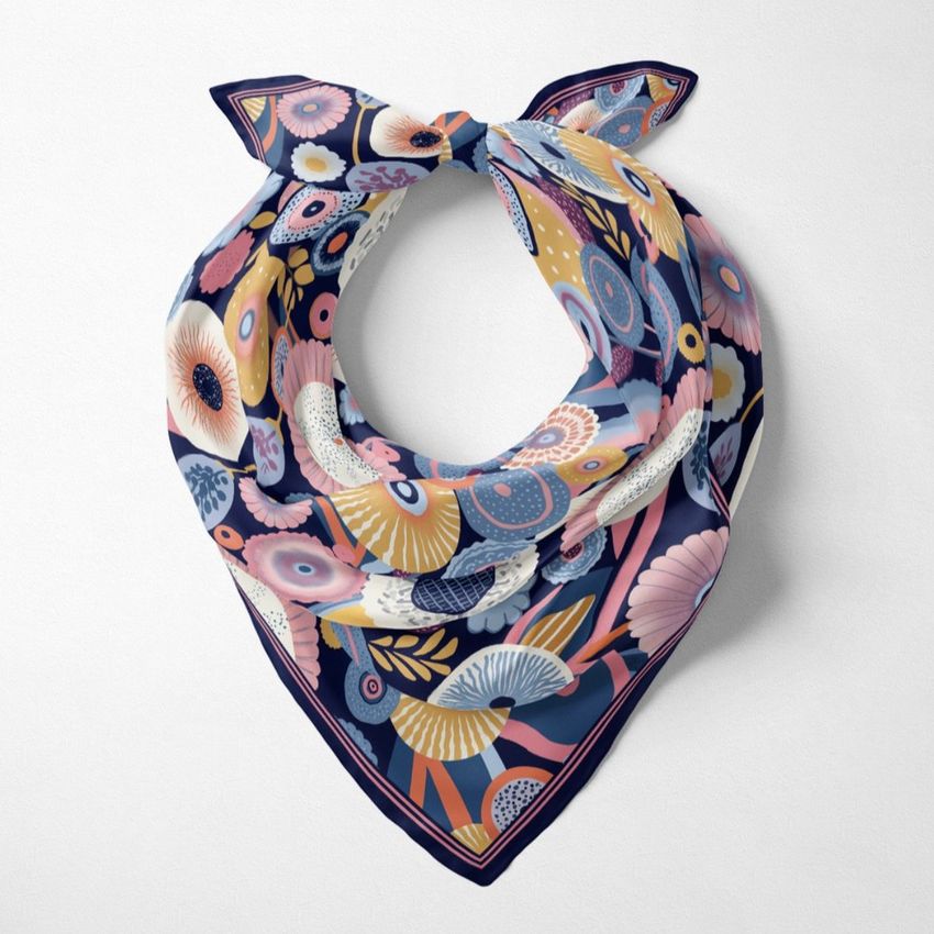 Top view of a wrapped silk scarf mockup featuring a colorful floral pattern in pink, blue, and yellow on a white background.
