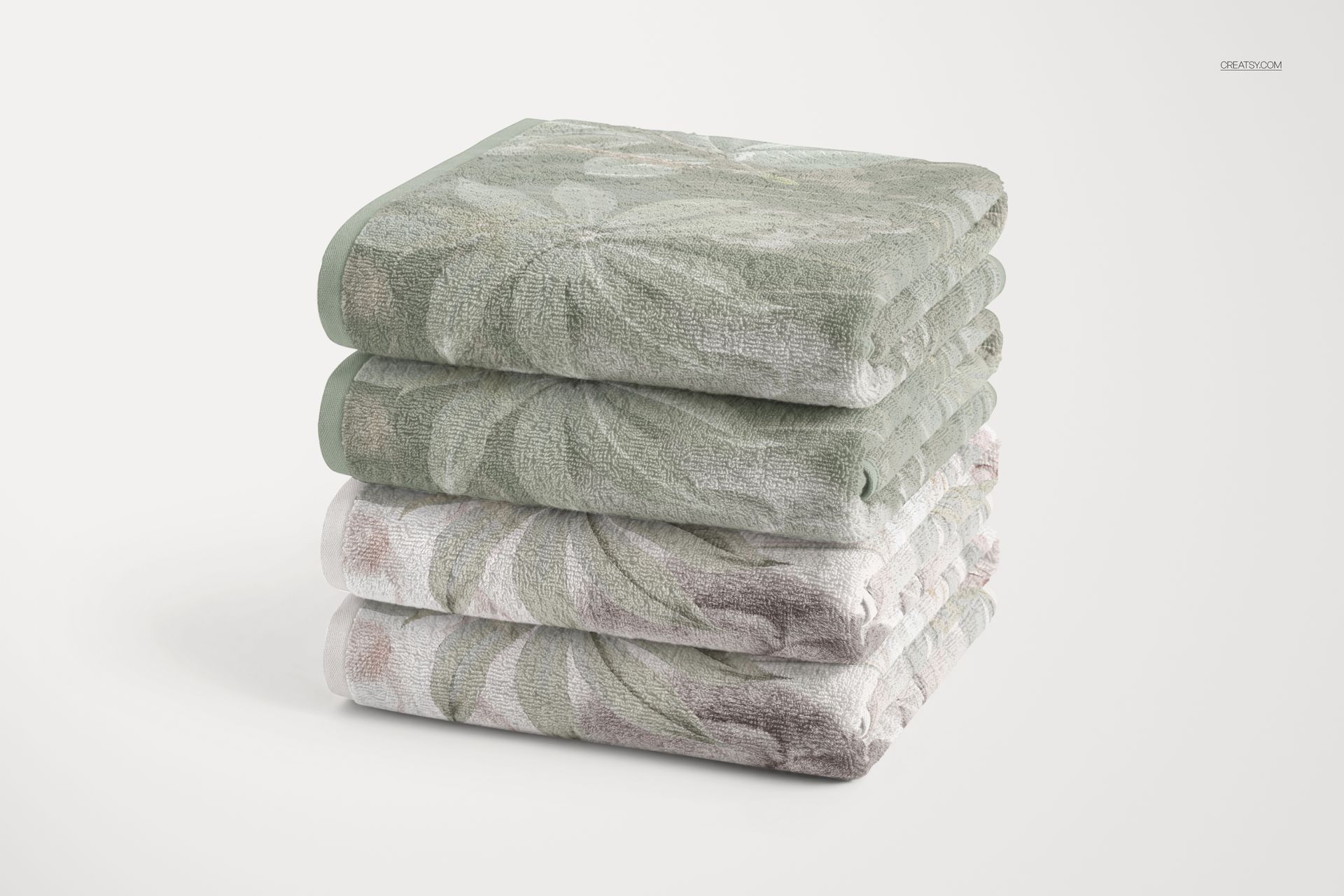 PSD mockup showing a stack of patterned towels in light green and beige hues, arranged neatly on a white surface.