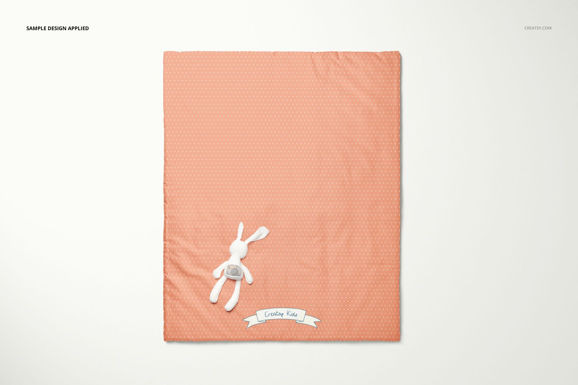 Baby fleece patchwork quilt mockup in peach with tiny dots, displayed flat on light background beside stuffed bunny.