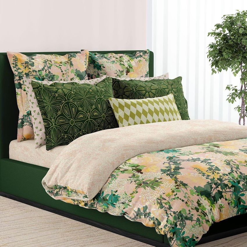 Bedding mockup featuring a bed with green and floral-patterned pillows and a comforter in a modern bedroom scene.