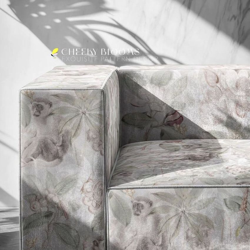 Velvet sofa mockup closeup showing arm and seat with floral and monkey pattern in soft pastel tones, marble wall background.