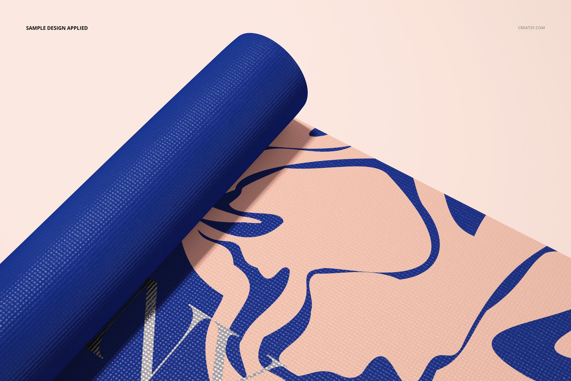 Close-up view of a yoga mat mockup with textured blue edge and abstract pink and blue artwork on a light background.