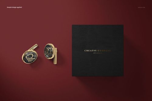 PSD mockup showing gold cufflinks with dark marbled accents and a textured black box on a burgundy background.