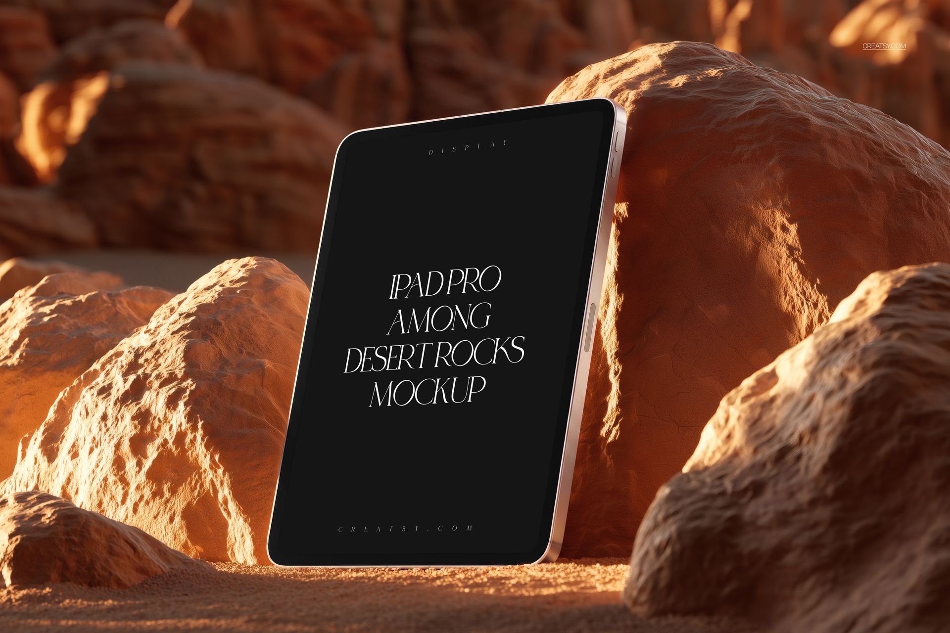 PSD mockup of an iPad Pro displayed vertically against sandy desert rocks, illuminated by natural sunlight.