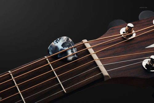 PSD mockup showing a detailed guitar pick placed on the neck and strings of a guitar, with metallic tuning pegs visible.
