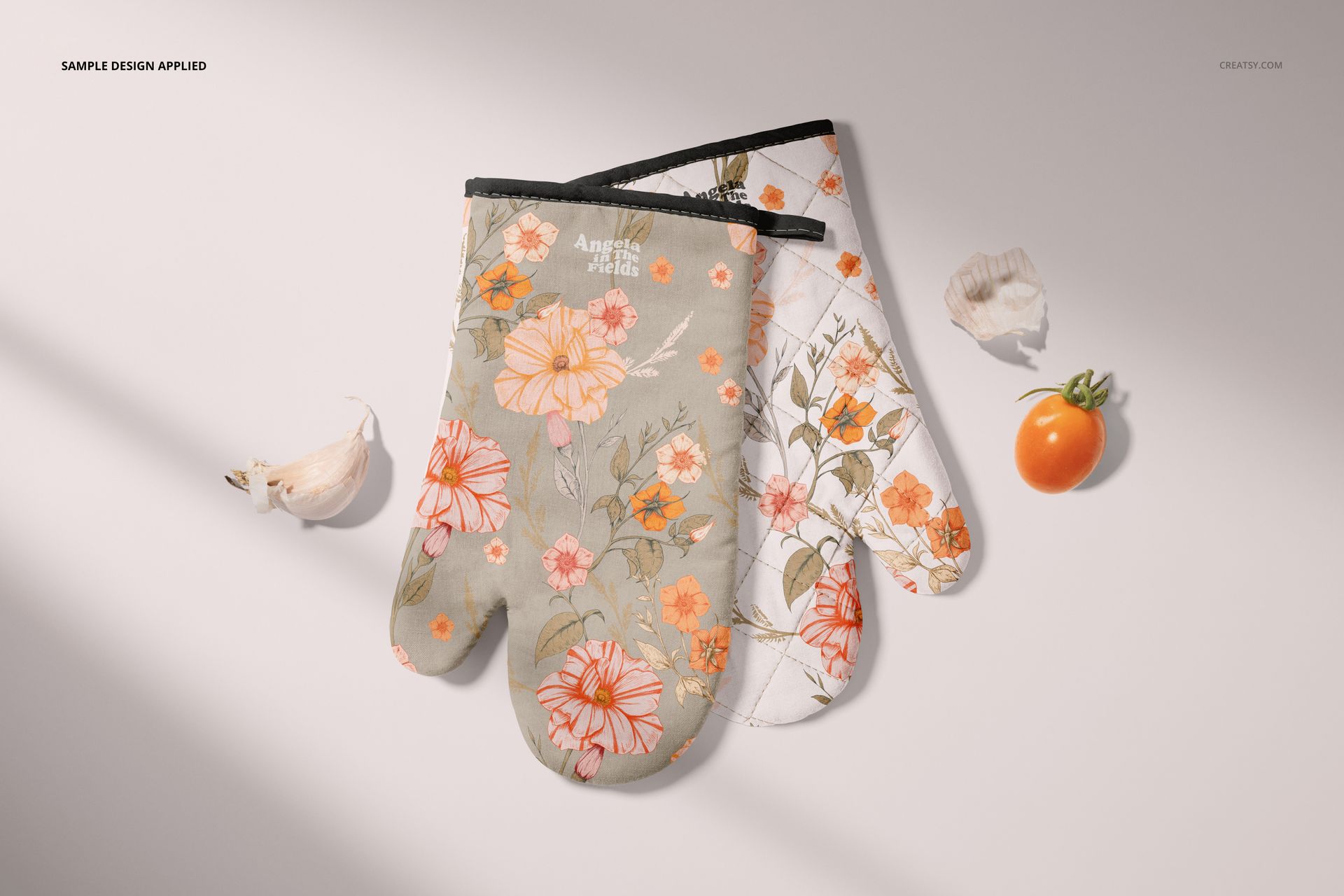 Oven mitt PSD mockup set with layered floral prints, presented on a neutral background with shells and vegetables.