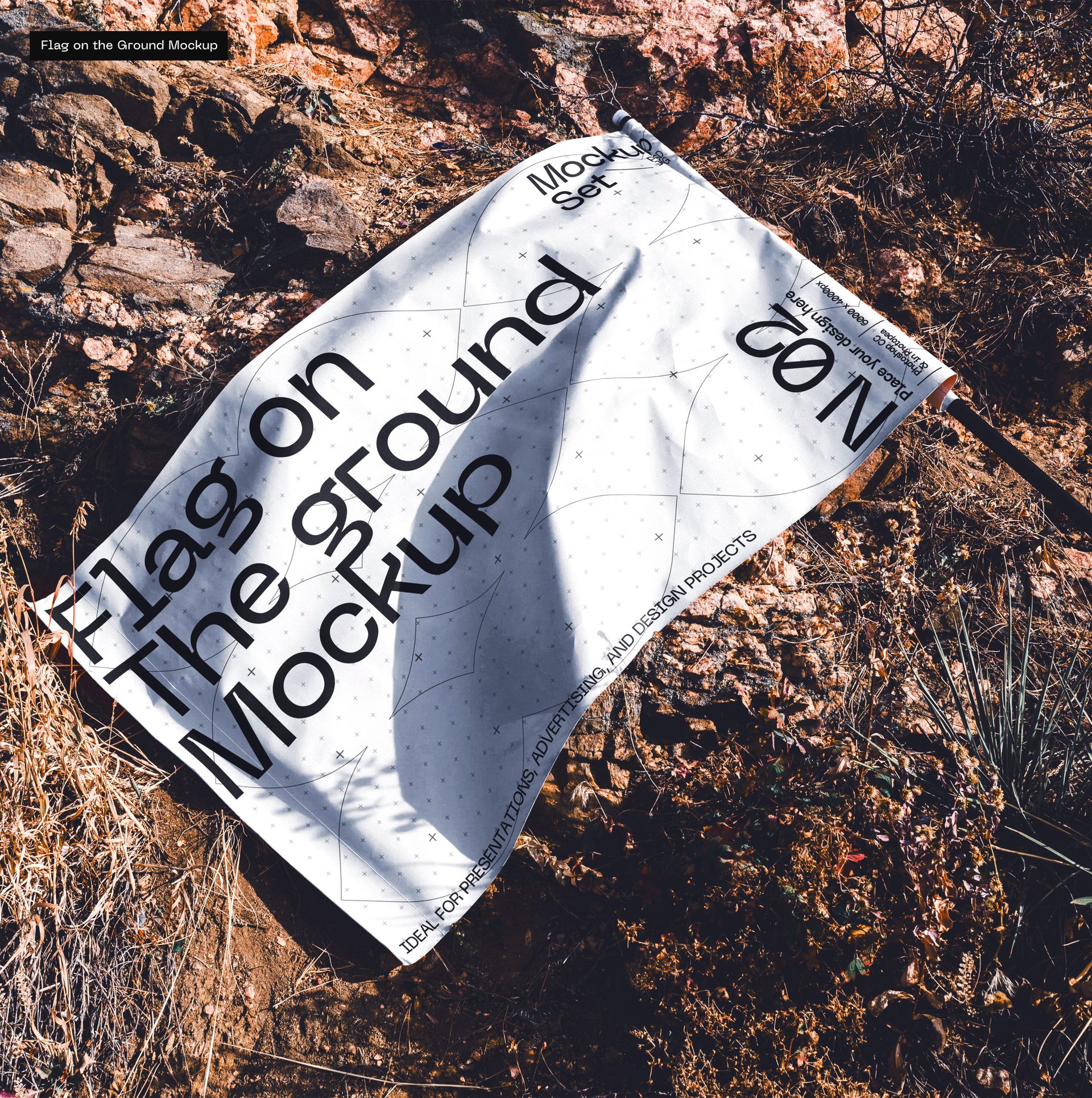 White advertising flag mockup displayed on uneven rocky terrain, viewed from above in bright daylight.