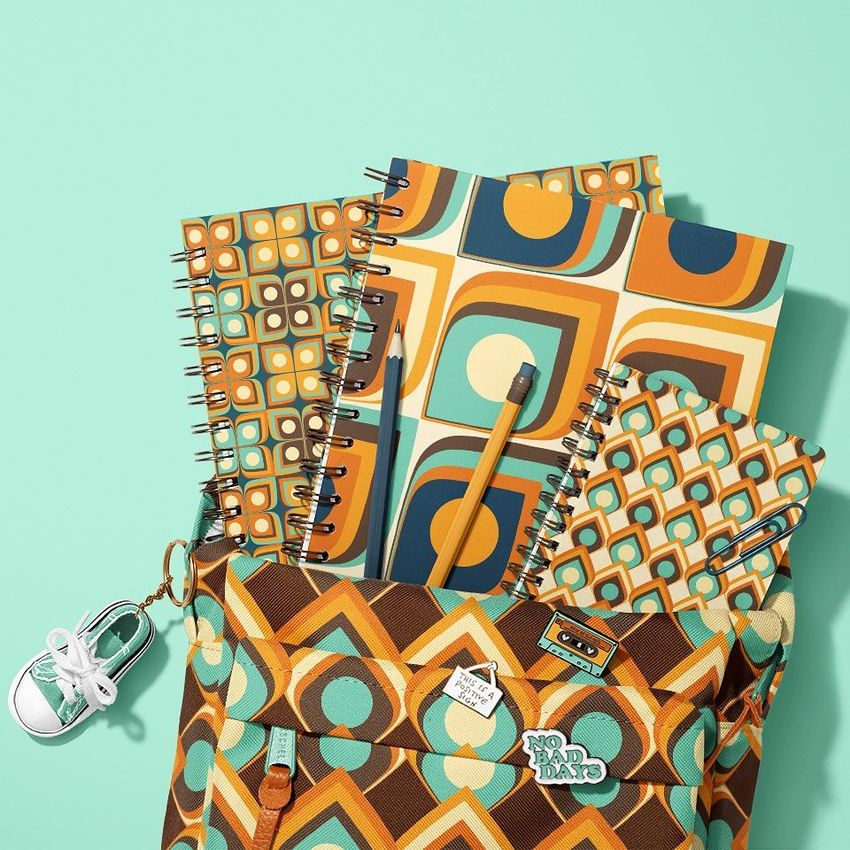 School backpack mockup with three spiral notebooks in retro geometric patterns, pencils, and a sneaker keychain on a mint background.