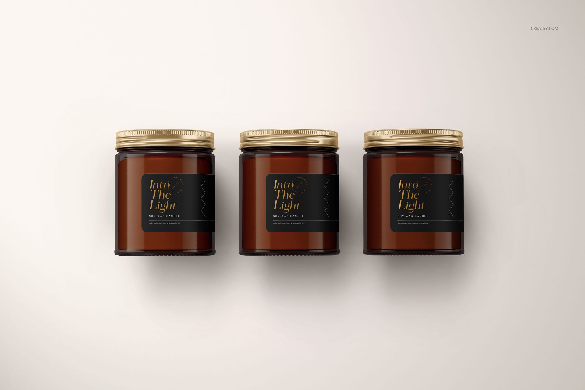 Amber jar candle PSD mockup showing three jars with gold lids and black labels arranged in a row, front perspective.
