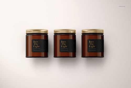 Amber jar candle PSD mockup showing three jars with gold lids and black labels arranged in a row, front perspective.
