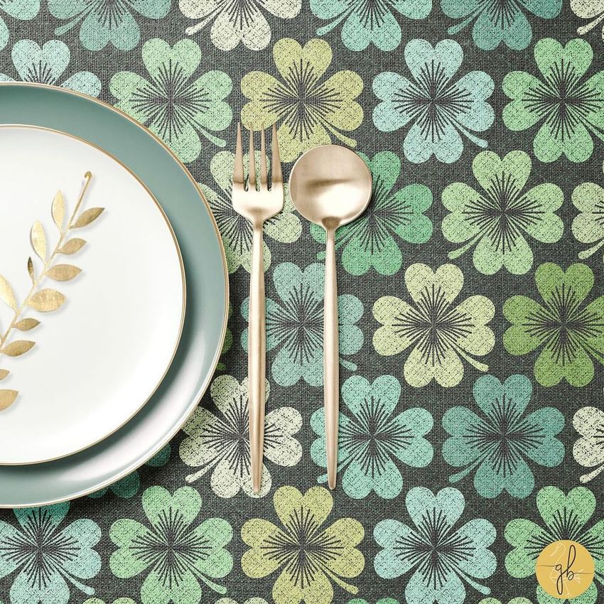 Placemat mockup showing a white plate with a gold leaf design, gold cutlery, and a green floral pattern background.