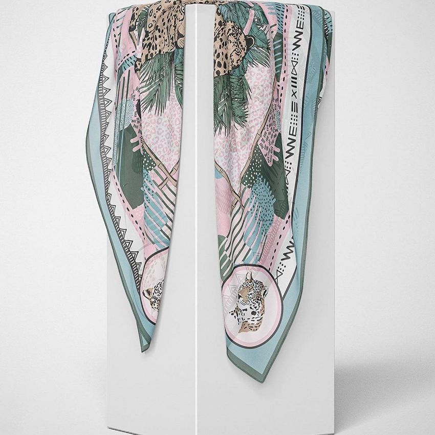 Silk scarf mockup draped over a white pedestal, featuring a pastel animal and leaf pattern with geometric borders.