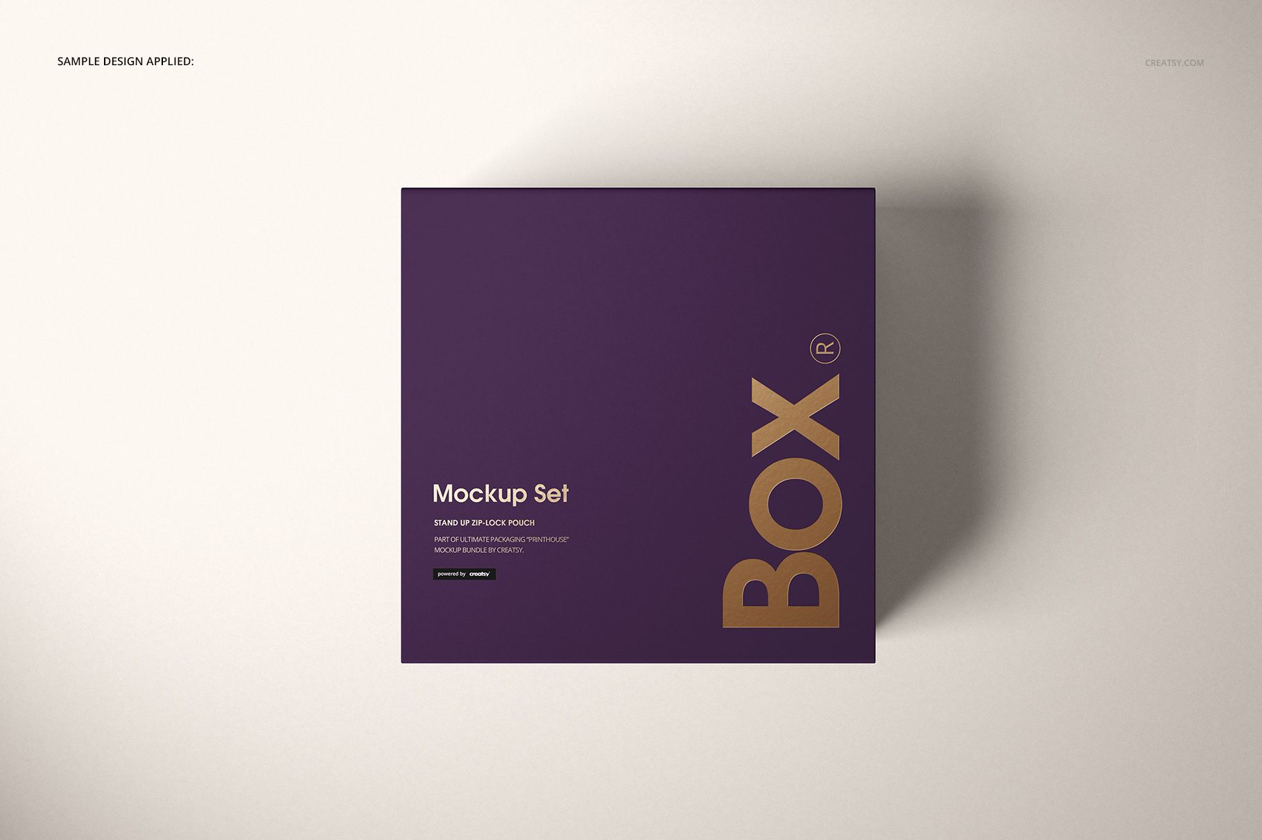 Top view of a magnetic gift box mockup featuring a purple lid with bold gold text, placed on a neutral surface.