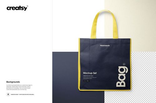 Front view of a non-woven tote bag mockup with yellow handles and trim, featuring a dark blue body and white text.