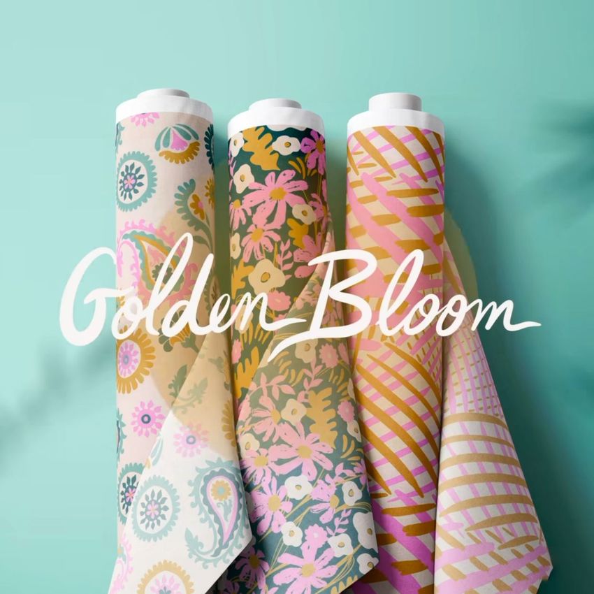 Fabric rolls mockup displaying three upright rolls with colorful floral and geometric patterns against a teal background.