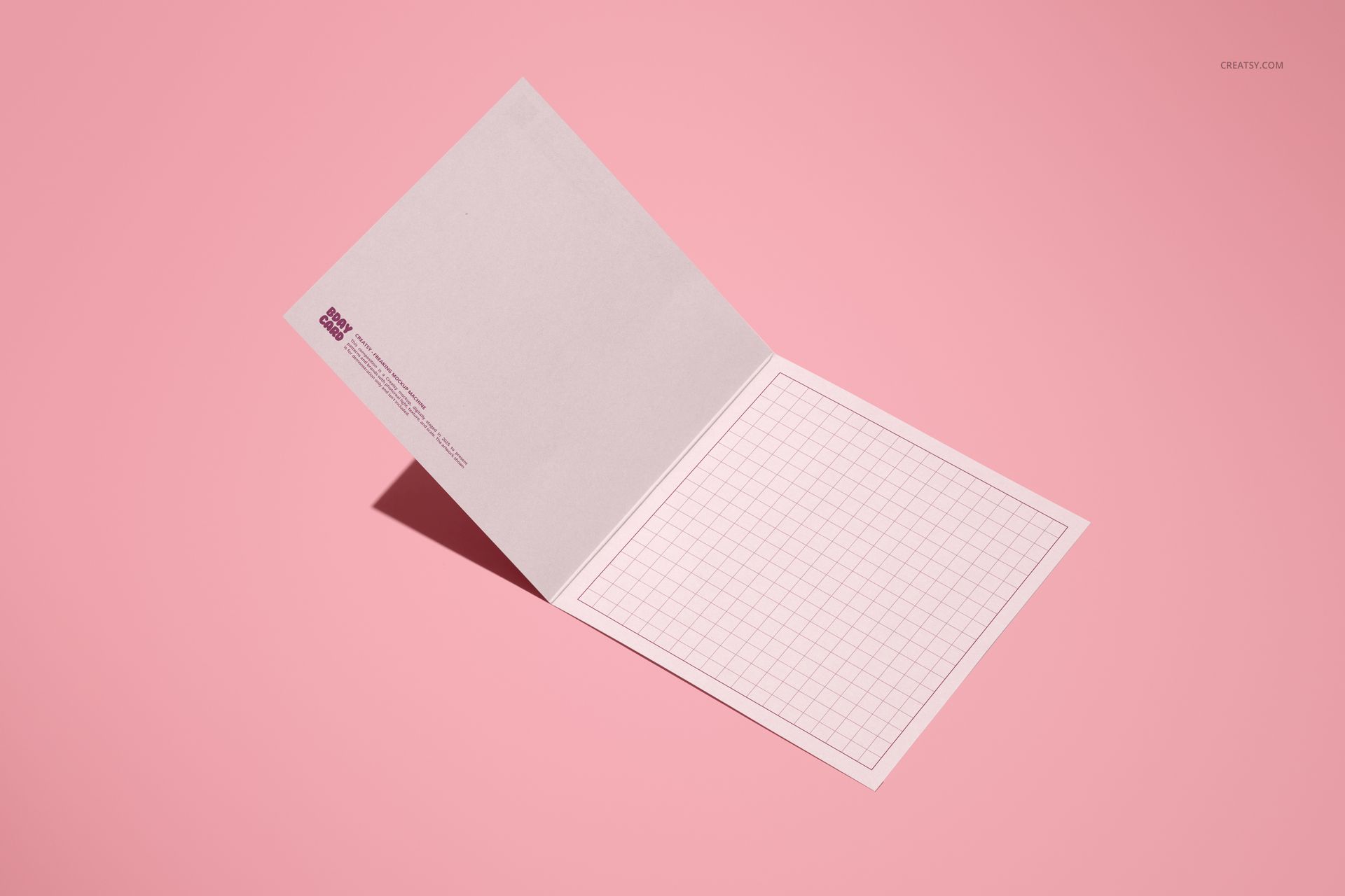Small square greeting card mockup displayed open on a pink background, showing grid pattern inside.