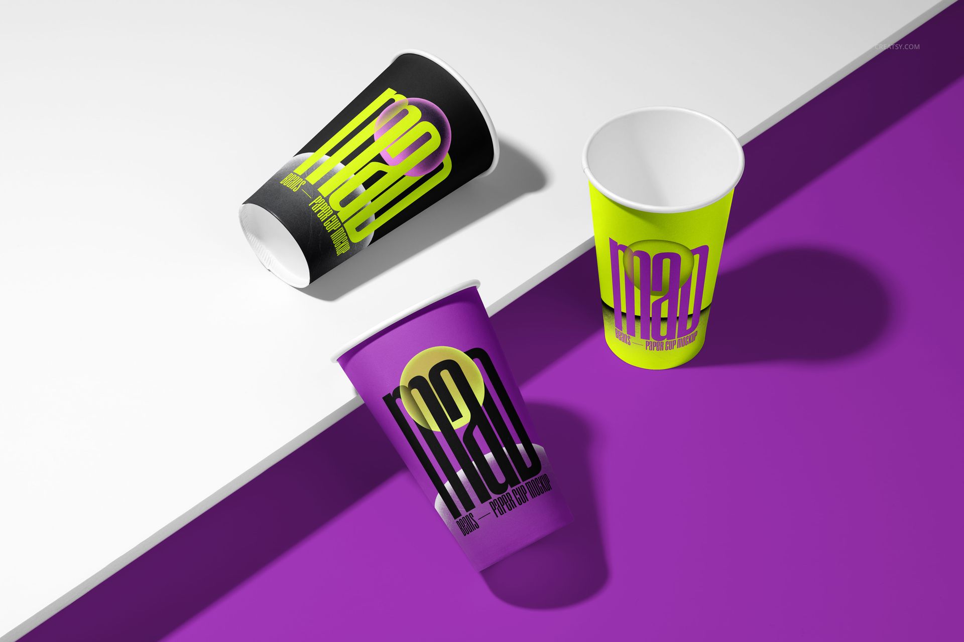 Paper cup mockup set featuring three cups with vibrant graphic prints in black, yellow, and purple, shown from an angled top view.