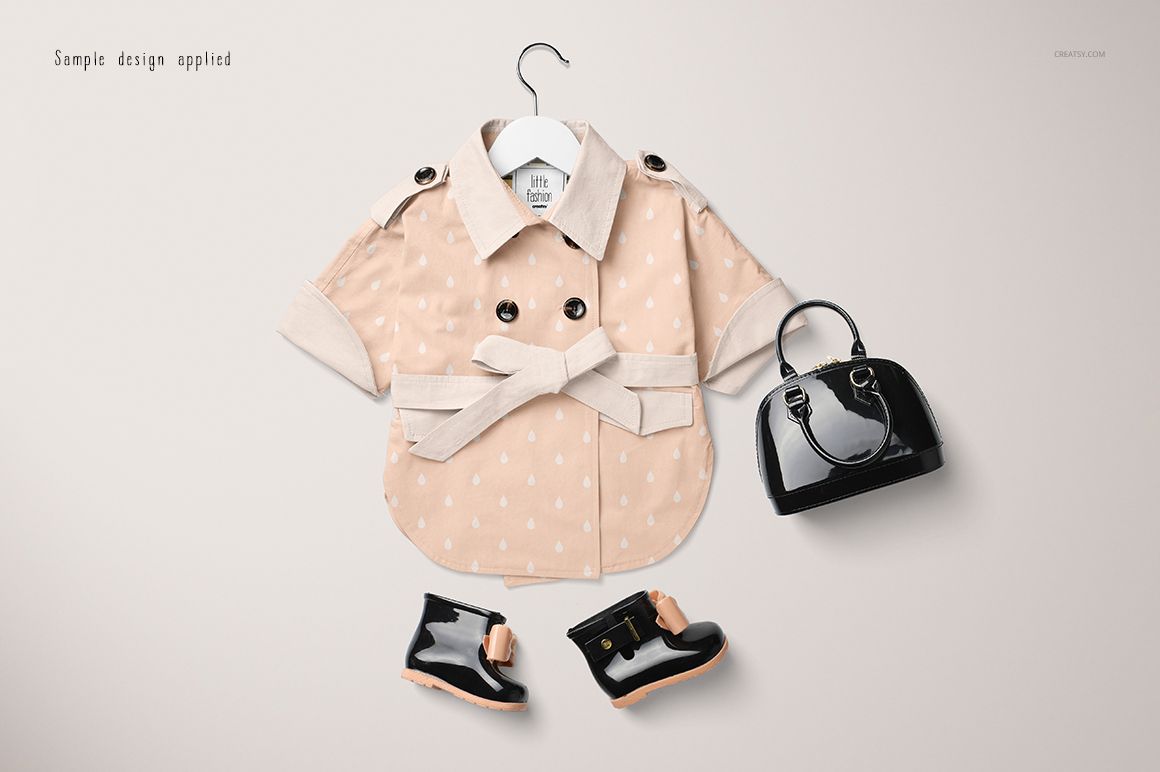 Baby coat mockup in beige with small white dots, shown on a hanger alongside glossy black shoes and a purse.