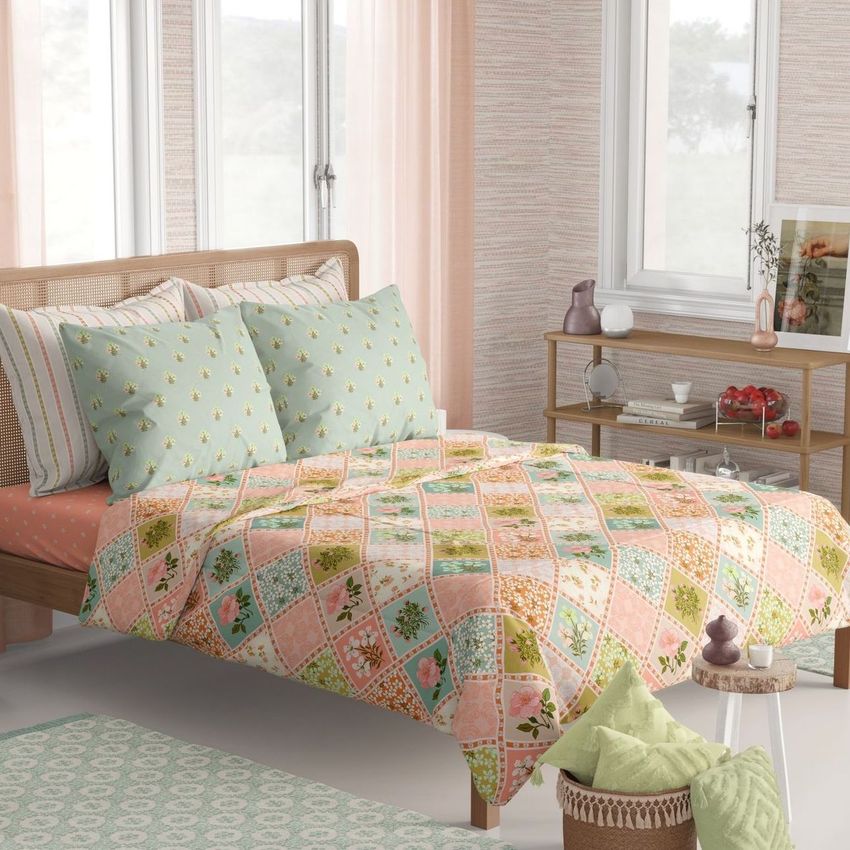 Boho bedroom bedding mockup featuring a quilt with colorful floral and geometric patterns, pastel pillows, and a wooden bed frame.