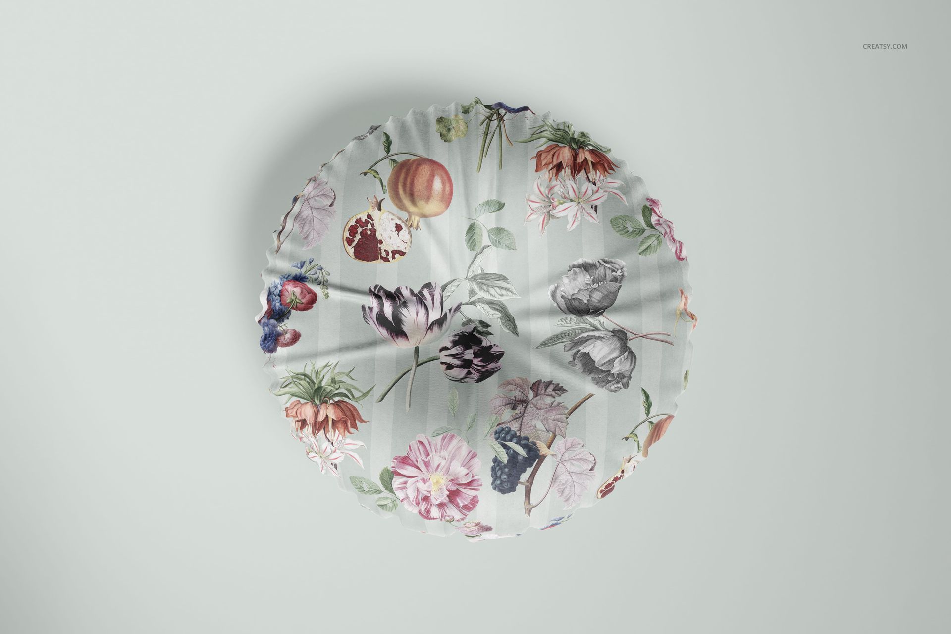 Floor pillow mockup with botanical and fruit illustrations, top-down perspective on a light gray surface.