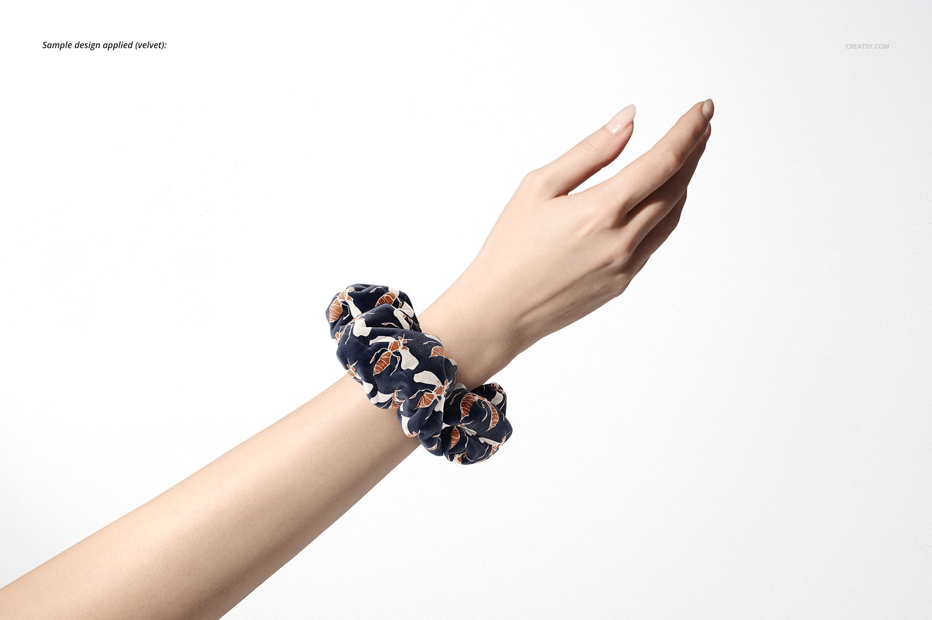 PSD mockup showing a patterned hair scrunchie worn on an extended hand, set against a minimal white backdrop.