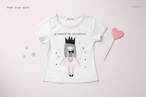 Front view of a girls T-shirt mockup with a cartoon princess design, white fabric, pink collar, and decorative props.