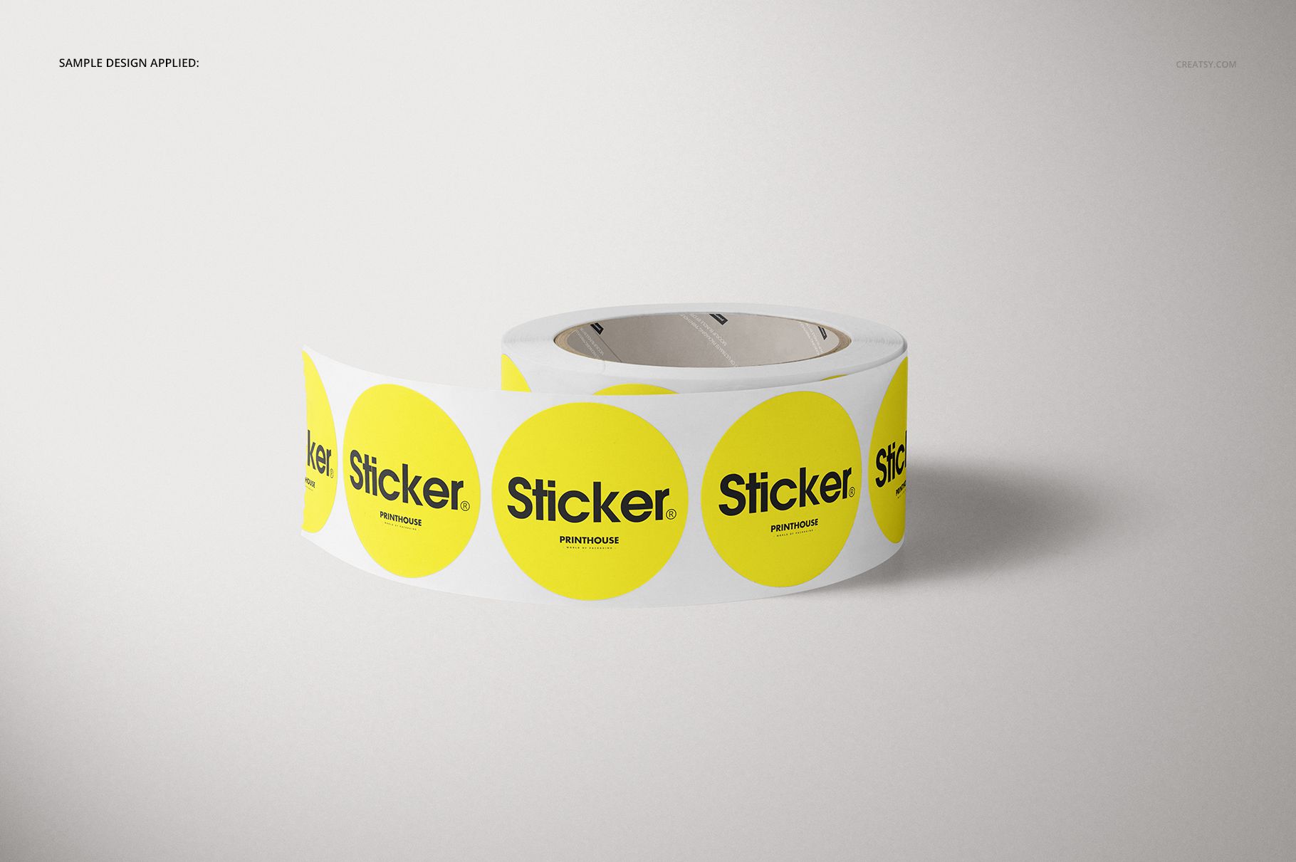 Front view of a round roll sticker mockup featuring yellow stickers with bold black lettering on a neutral surface.