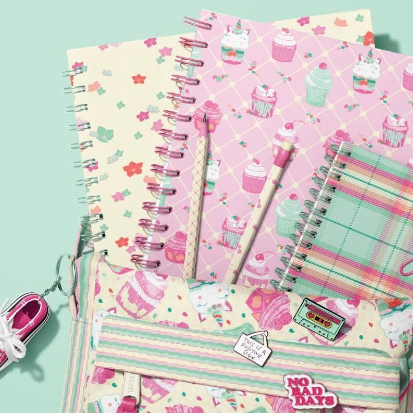 School backpack mockup with spiral notebooks, pencils, and a bag featuring pastel cupcake patterns on a mint green background.