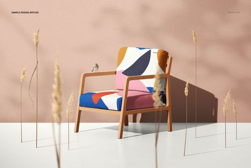 Lounge chair mockup featuring a bold multicolor fabric design, wooden arms, and decorative dried grass in the scene.