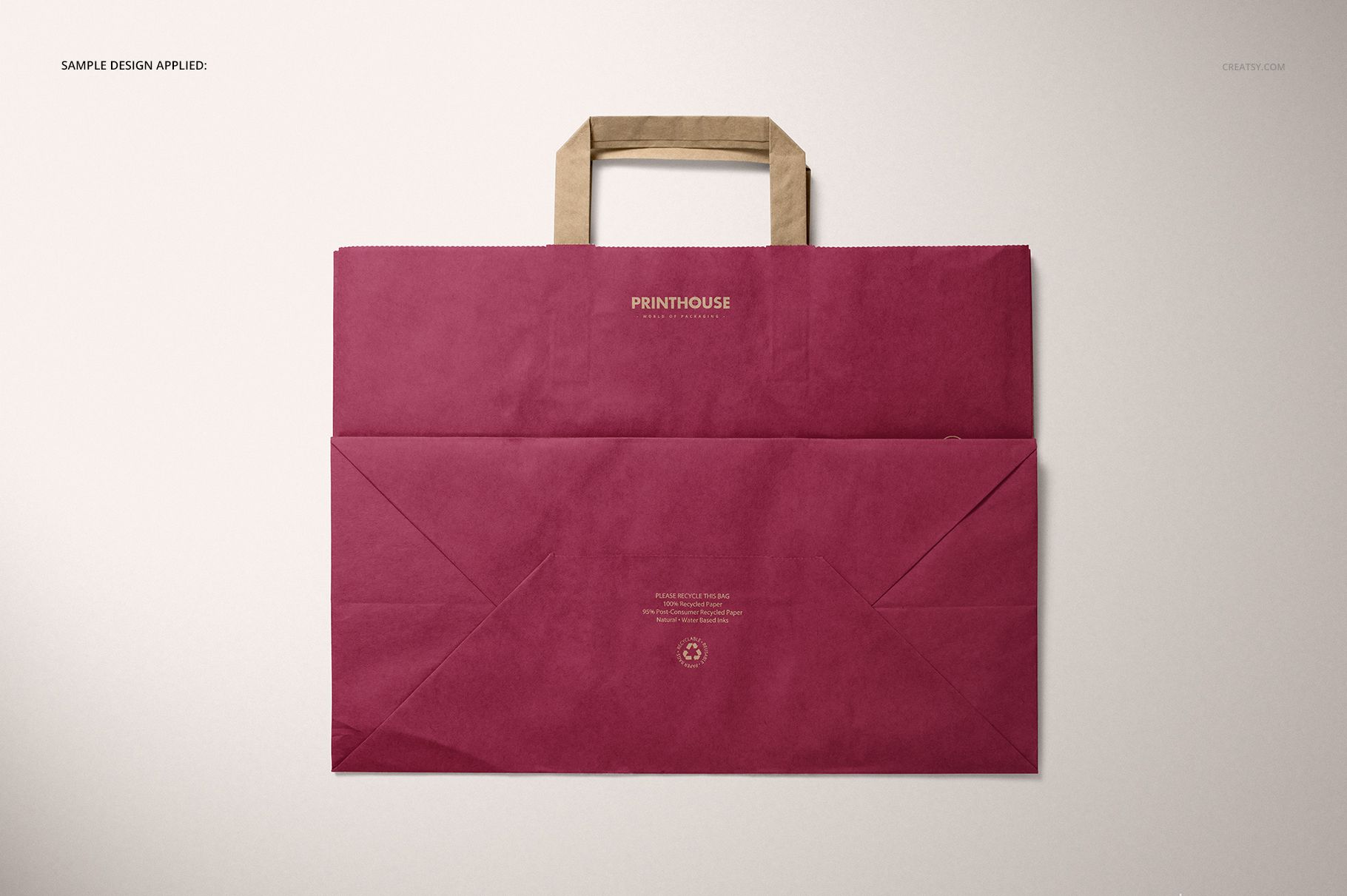 Burgundy kraft paper bag mockup with folded handles shown from above, placed on a neutral background.