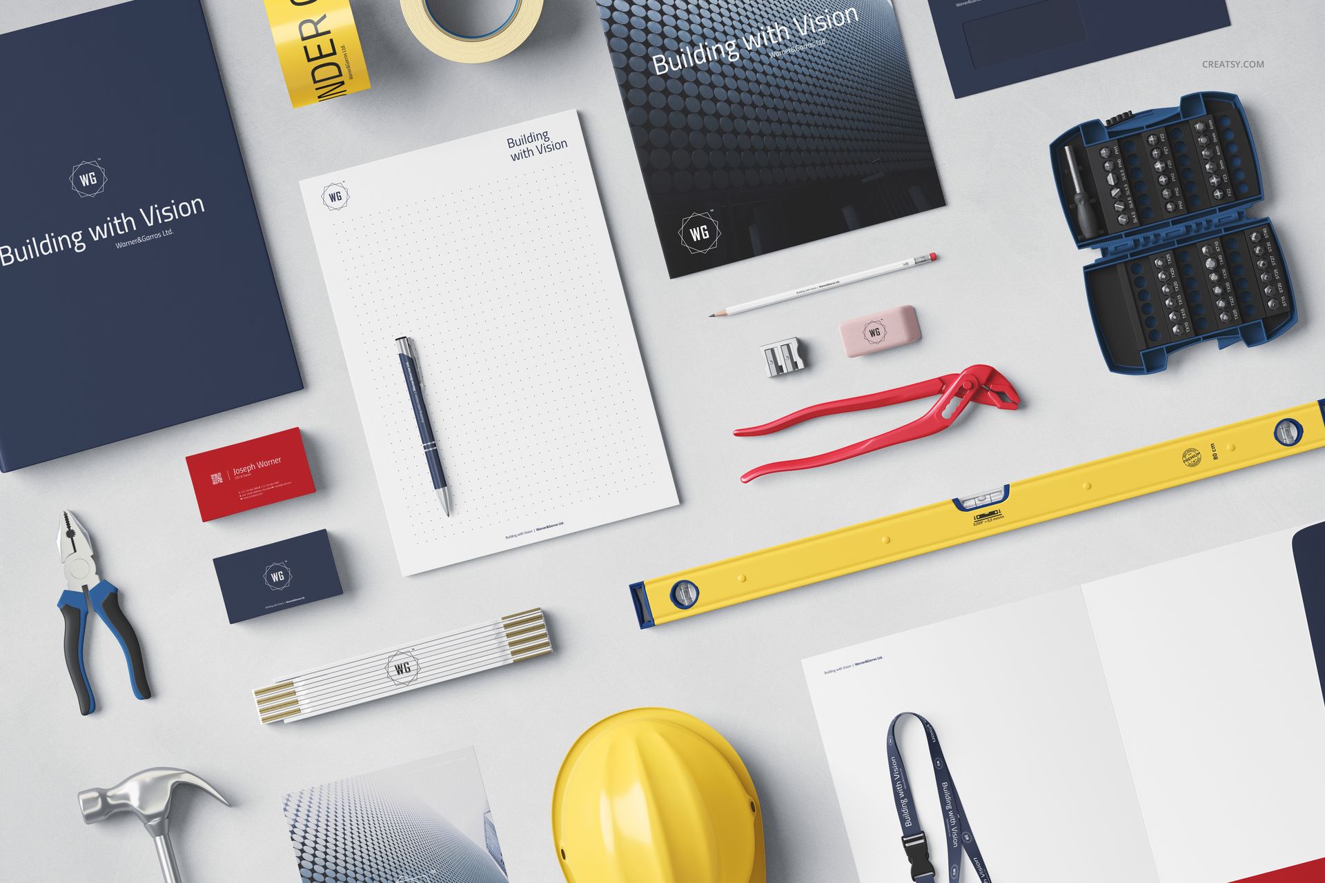 Construction company identity mockup set with stationery, business cards, tools, and safety helmet arranged on a light surface.