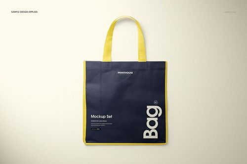 Front view of a non-woven tote bag mockup with yellow handles and edges, featuring a dark blue body on a neutral background.