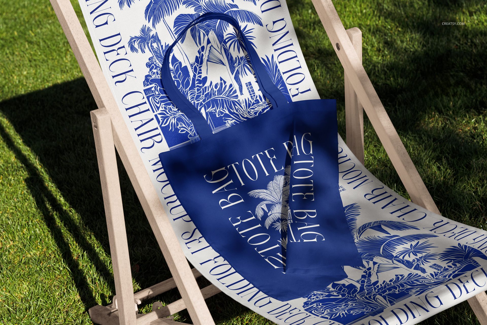 Front view of a folding deck chair mockup outdoors on grass, with blue and white patterned fabric and matching tote bag.