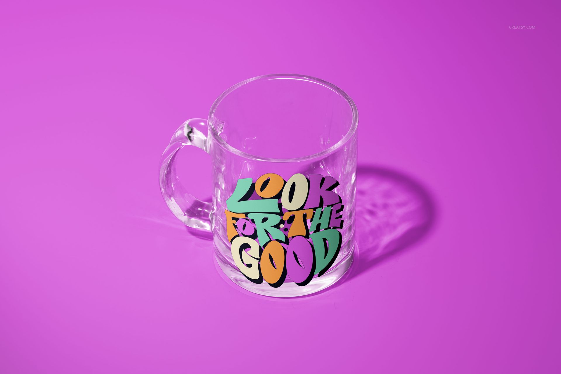 PSD mockup of a glass mug with bold, graphic text in green, yellow, and purple, displayed against a purple backdrop.