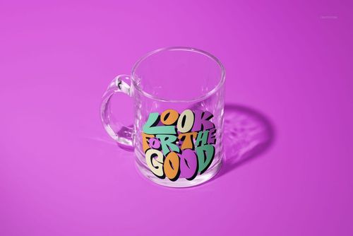 PSD mockup of a glass mug with bold, graphic text in green, yellow, and purple, displayed against a purple backdrop.